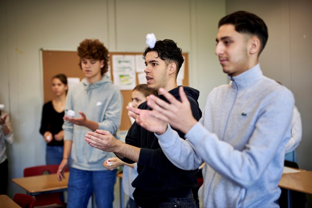 Jugendliche werfen Kugeln aus zerknülltem Papier in die Luft.