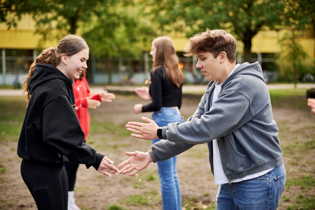 Jugendliche stehen sich gegenüber und spielen ein Spiel mit ihren Händen.