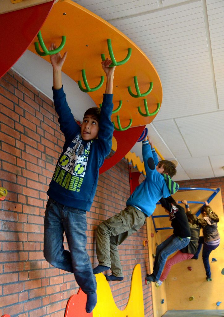 Mehrere Kinder hangeln an einer Kletterwand.